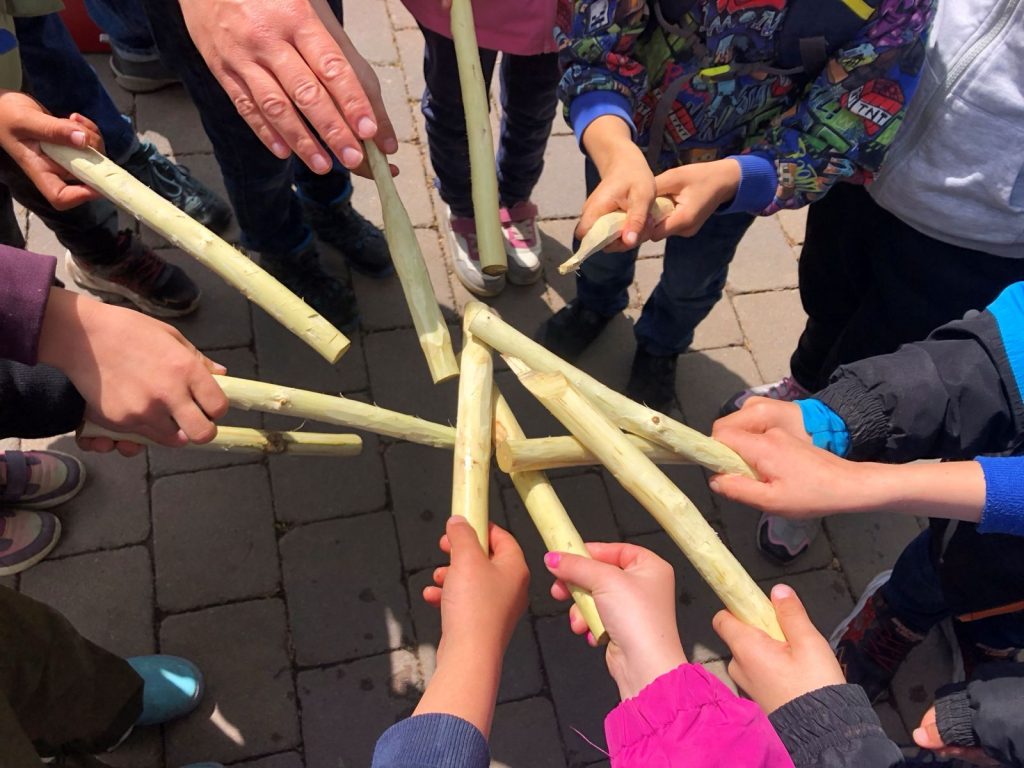 Kinder halten ihre selbst geschnitzte Stöcke in die Mitte